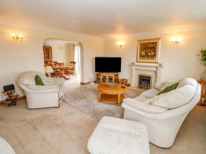 a living room with white furniture and a fireplace at Corner House in Cinderford