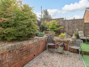 een tuin met 2 stoelen en een bakstenen muur bij Corner House in Cinderford