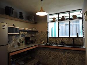 een keuken met een fornuis, een magnetron en een raam bij Casa cómoda con patio a 4 cuadras de la catedral. in Oaxaca City