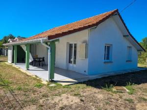 une petite maison blanche avec un grand porche dans l'établissement La Cabane aux lacs ~ Maison cosy au calme, à Aureilhan