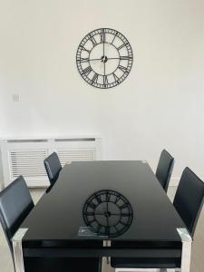 une table noire avec des chaises et une horloge sur le mur dans l'établissement 3 Bedroom Entire Flat, Luxury facilities with Affordable price, Self Checkin/out, à Fife