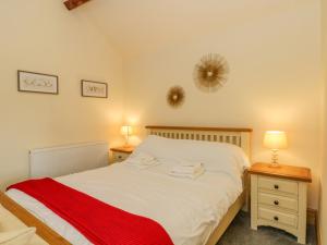 a bedroom with a bed with a red blanket on it at Swallows Nest in Macclesfield