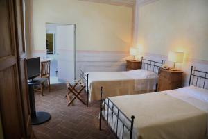 アレッツォにあるラ ロカンダ ディ サン ピエール ピッコロのベッド2台とテレビが備わるホテルルームです。
