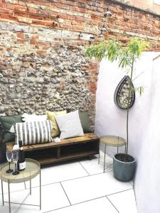 un patio con sofá, 2 mesas y una pared de ladrillo en City Apartment, 2 min walk to Norwich centre. en Norwich