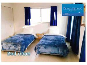 two beds in a bedroom with blue curtains and a window at Kaoru Resort Enoshima - Vacation STAY 08572v in Fujisawa