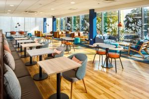 un restaurante con mesas, sillas y ventanas en ibis budget London Heathrow Central, en Hounslow