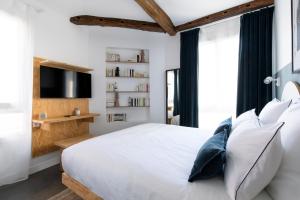a bedroom with a white bed and a tv at Baba Hotel in Paris