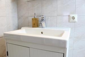 a white sink in a bathroom with white tiles at Ferienwohnung Krohn Cuxhaven in Cuxhaven