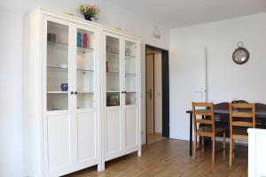 a white cabinet in a dining room with a table at Ferienwohnung Krohn Cuxhaven in Cuxhaven