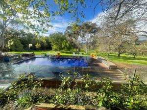 a swimming pool in a garden with a wooden deck at Nest on the Hill - A Luxurious Escape in Red Hill South