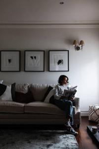 a woman sitting on a couch reading a book at Nest on the Hill - A Luxurious Escape in Red Hill South