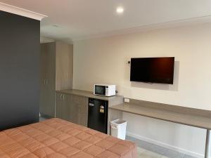 a hotel room with a bed and a flat screen tv at Homestead Motel in Dubbo