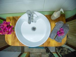 lavabo blanco en un baño con flores en Uka O Te Ra´a Cabaña full equipada., en Hanga Roa