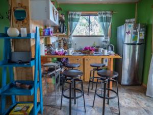a kitchen with a counter with stools and a refrigerator at Uka O Te Ra´a Cabaña full equipada. in Hanga Roa
