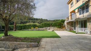 um quintal com um relvado verde em frente a uma casa em Holidays en Arenys de Mar y Montaña em Arenys de Mar