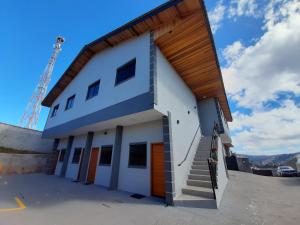 a large white building with stairs on the side at Alpes Flats in Campos do Jordão