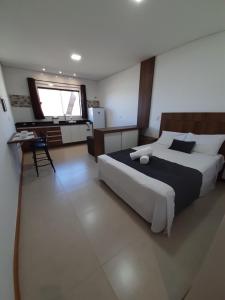 a bedroom with a large bed and a kitchen at Alpes Flats in Campos do Jordão