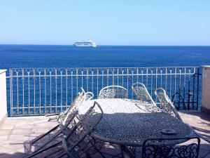 un tavolo e sedie su un balcone con vista sull'oceano di Perla di Naxos a Giardini Naxos