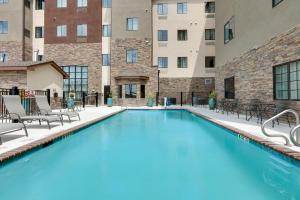 een zwembad met stoelen en een gebouw bij Staybridge Suites - San Antonio - Schertz, an IHG Hotel in Schertz