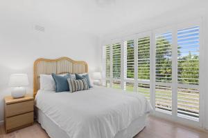 een witte slaapkamer met een bed en een groot raam bij Swell@Blairgowrie - Sleeps nine! in Rye