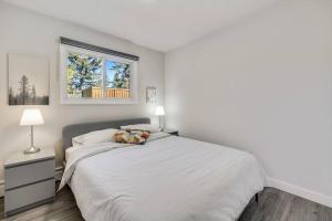 a white bedroom with a bed and a window at Roxboro #1 Premium Central 3BR Home Parking, Wifi in Calgary