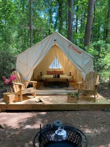 a tent with a bed and two chairs in a forest at Tentrr Signature Site - Herb'n Soul Sanctuary in Stone Mountain