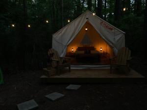 a tent with two chairs and a bed in the woods at Tentrr Signature Site - Herb'n Soul Sanctuary in Stone Mountain