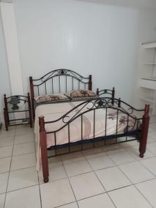 Les Gîtes de Fond Bellemare في Case-Pilote: سرير معدني في غرفة مع أرضية من البلاط