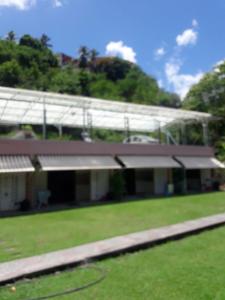 a building with a green field in front of it at Les Gîtes de Fond Bellemare in Case-Pilote