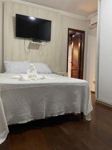 - une chambre avec un lit blanc et une télévision murale dans l'établissement Hostel Salvador Orquídeas, à Salvador