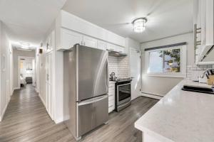 una cocina con nevera de acero inoxidable y armarios blancos en Roxboro #2 Premium Central 3BR Home Parking, Wifi, en Calgary