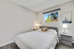 a white bedroom with a bed and a window at Roxboro #2 Premium Central 3BR Home Parking, Wifi in Calgary