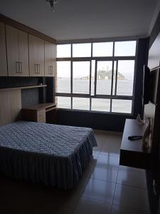 a bedroom with a bed and a large window at Lar de férias in São Vicente