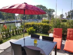 ein Tisch mit einem roten Sonnenschirm auf einer Terrasse in der Unterkunft Kapitänsresidenz - Haus direkt am Wasser in Ückeritz