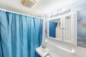 a bathroom with a blue shower curtain and a sink at Shorely Suite in Atlantic Beach