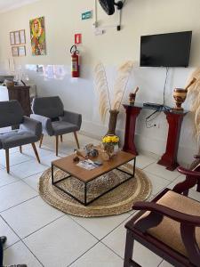 a living room with chairs and a table and a tv at Bom Sossego Pousada DG in Delmiro Gouveia