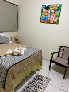 a bedroom with a bed and a chair and a painting at Bom Sossego Pousada DG in Delmiro Gouveia