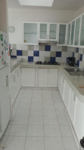 una cocina con armarios blancos y azulejos azules y blancos en Casa de playa, Palabitas, Asia del Sur, en Asia