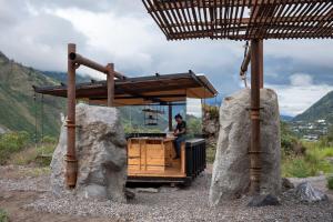 a man standing in a wooden bar on a truck with two large rocks at Stunning cabin in Baños in Baños
