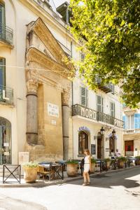 a woman walking down a street in front of a building at Grand Hôtel Nord-Pinus in Arles