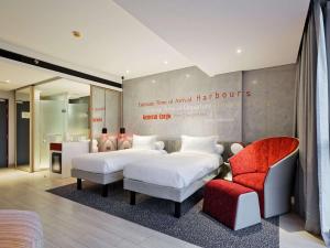 una habitación de hotel con 2 camas y una silla en ibis Styles Batam Nagoya en Nagoya