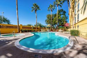 a swimming pool with palm trees and a building at La Quinta by Wyndham Phoenix West Peoria in Peoria