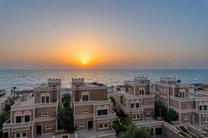 Wyndham Residences The Palm في دبي: اطلالة على المحيط والمباني وقت الغروب