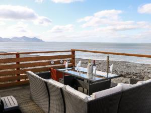 a patio with a table and chairs on the beach at Swn Y Mor in Caernarfon