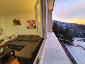 un soggiorno con un divano e una grande finestra di Maribel ERB Alojamientos a Sierra Nevada