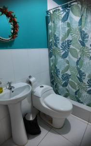y baño con aseo, lavamanos y cortina de ducha. en Hostal Brisa Marina, en Paracas