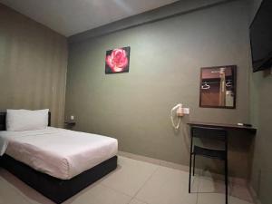 ein Schlafzimmer mit einem Bett und einer rosa Rose an der Wand in der Unterkunft Parc Hotel Pelangi Damansara in Kota Damansara