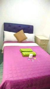 a bedroom with a pink bed with a purple blanket at 25th RESIDENCES- LACSON BACOLOD in Bacolod