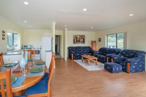 a kitchen and a living room with a table and a couch at Hosts on the Coast Laze Away on Cook in Cooks Beach