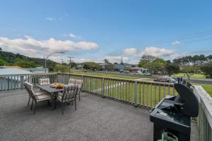 a patio with a table and chairs on a balcony at Hosts on the Coast Laze Away on Cook in Cooks Beach